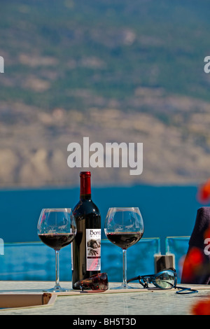 Rotwein in Weingläsern und Flasche Wein auf einer Terrasse Tisch mit Blick auf Okanagan Lake von Bonitas Weingut, Summerland, Okanagan Stockfoto