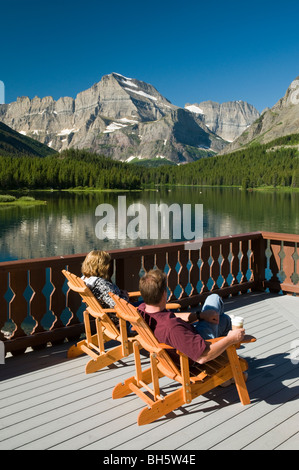 Ein paar genießt die Aussicht auf Swiftcurrent Lake und Mt. Gould aus dem Deck im Many Glacier Hotel Stockfoto