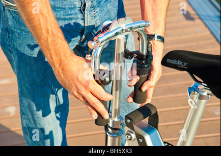 Mann, die Entfaltung einer Mobiky Klapprad auf einem Bootssteg mit Yachten Stockfoto