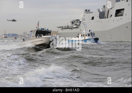 Crews aus der Küstenwache und Polizei Abteilungen escort USS New York, wie es in New York Hafen fährt. Stockfoto