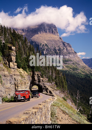 USA, Montana, Glacier NP. Vintage red Jammer Tourbus auf Going-to-the-Sun Parkway von Going-to-the-Sun Mt. Stockfoto