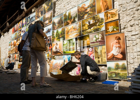 Menschen betrachten & kaufen Sie ein Gemälde für den Verkauf an Touristen / Malerei zum Verkauf an Touristen am Kunstmarkt auf Pijarska. Krakau, Polen. Stockfoto