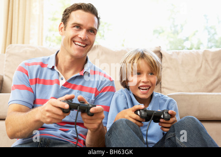 Vater und Sohn spielen Computerspiel auf Sofa zu Hause Stockfoto