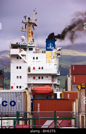 Ein Containerschiff Rauch aus Trichter während auf ein Container-terminal festgemacht Stockfoto