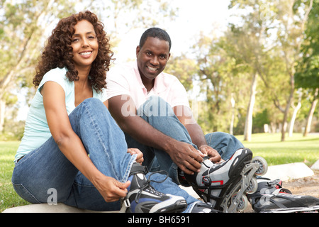 Paar anziehen In Line Skates im Park Stockfoto