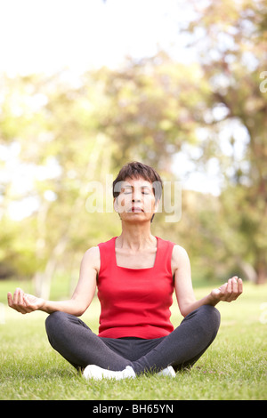 Ältere Frau beim Yoga im Park Stockfoto