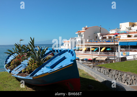 Ein altes Fischerboot bekommt ein neues Leben als einen Blumentopf auf einem Rasen durch die Restautants in La Caleta an der Westküste von Teneriffa Stockfoto