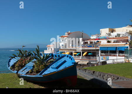 Ein altes Fischerboot bekommt ein neues Leben als einen Blumentopf auf einem Rasen durch die Restautants in La Caleta an der Westküste von Teneriffa Stockfoto