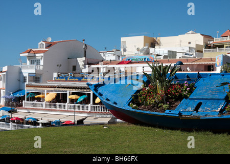 Ein altes Fischerboot bekommt ein neues Leben als einen Blumentopf auf einem Rasen durch die Restautants in La Caleta an der Westküste von Teneriffa Stockfoto