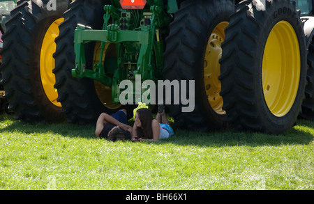 Dieses junge Teen paar erfreuen sich einen ruhigen Moment der Schatten zusammen unter einem Traktorreifen. Stockfoto