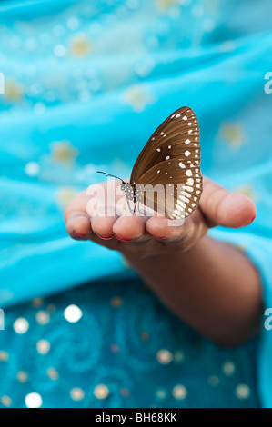 Euploea core. Gemeinsame Krähe Schmetterling auf der Hand eines indischen Mädchens. Andhra Pradesh. Indien Stockfoto