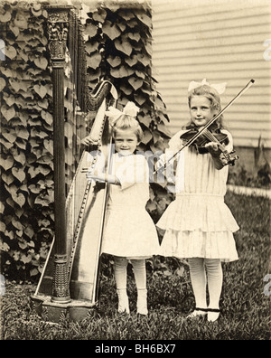 Kleinen Schwestern spielen Harfe & Violine Stockfoto