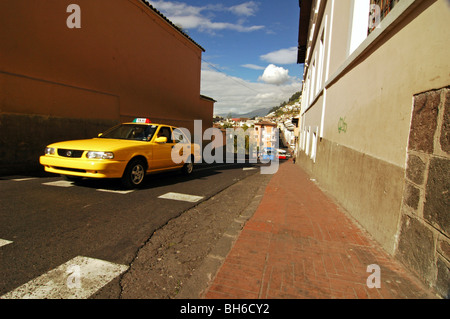 Ecuador, Quito, Yellow Cab auf einer schmalen Straße durch einen Bürgersteig, Stadtbild von Quito in Equador in einem Abstand und Hügel von El Panecill Stockfoto