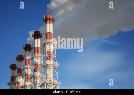 Fünf Schornsteine mit Dampf auf blauen Himmelshintergrund. Stockfoto