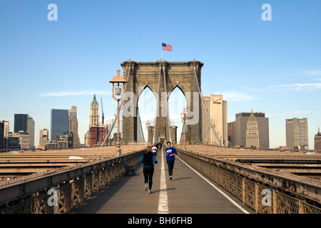 Jogger laufen über die New Yorker Brooklyn Bridge an einem klaren sonnigen Morgen Stockfoto