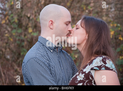 Ein paar der kaukasischen genießen einen süßen romantischen Kuss im Freien.  Guy hat einen rasierten Kopf und Frau hat lange brünette Haare und sind in der Liebe Stockfoto