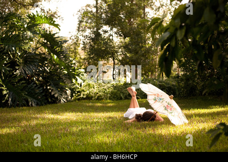Eine Mädchen entspannt auf dem Rasen unter ihrem chinesischen Dach. Stockfoto