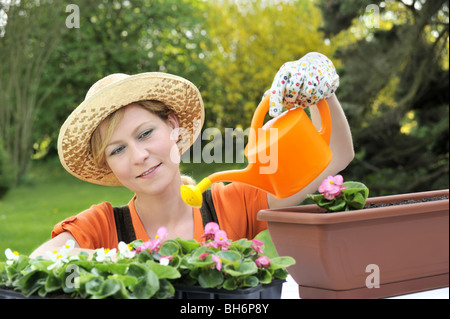 Junge Frau Bewässerung Blumen Stockfoto