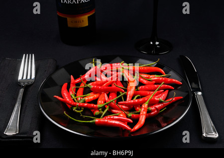 Vollen Teller von red hot Chili Peppers auf eine schwarze Tischdekoration mit Wein aus Chile Stockfoto