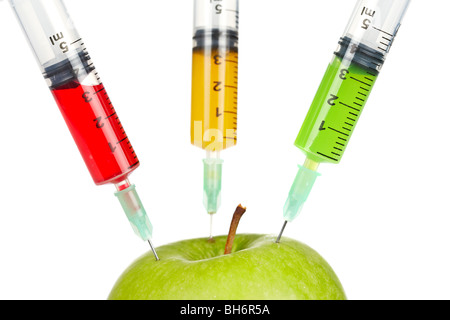 Ein grüner Apfel mit drei Spritzen mit Farbe Flüssigkeiten, isoliert auf weißem Hintergrund injiziert werden. Geringe Schärfentiefe Stockfoto