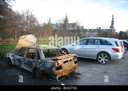 A Auto Kontrast zu neuen Modellautos und die Burg auf dem Parkplatz von Schloss Frederiksborg, Hilleroed, Dänemark ausgebrannt. Stockfoto