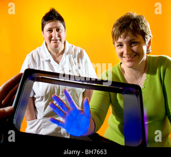 Krankenschwestern zeigen, wie die Bakterien auf den Händen bleiben können, wenn Sie nicht richtig gewaschen, mit Gel, das unter UV-Licht leuchtet. Stockfoto