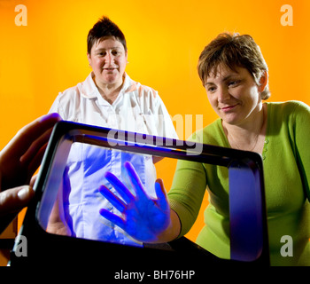 Krankenschwestern zeigen, wie die Bakterien auf den Händen bleiben können, wenn Sie nicht richtig gewaschen, mit Gel, das unter UV-Licht leuchtet. Stockfoto