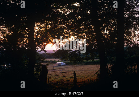 Ein Tageslicht verblasst durch Bäume, ein einsamer Wohnwagen ist in einem ruhigen Bereich mit Blick auf die North Somerset Landschaft aufgeschlagen Stockfoto