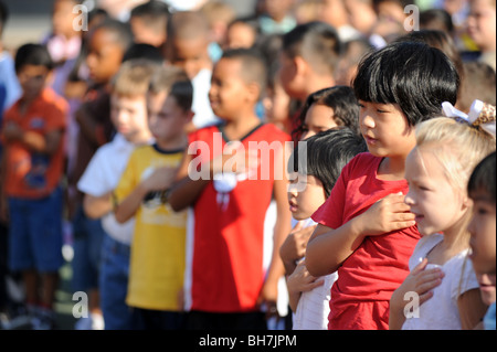 Grundschule Kinder in Massachusetts Volksschule Versammlung legen Hände über Herzen, die Pledge of Allegiance. Stockfoto