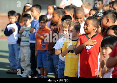 Grundschule Kinder in Massachusetts Volksschule Versammlung legen Hände über Herzen, die Pledge of Allegiance. Stockfoto