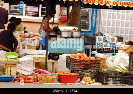 Ecuador, Otavalo, Tomaten, Zwiebeln und Karotten in Töpfe und Körbe auf einem Markt stall mit Frau im Hintergrund Prepaid Stockfoto