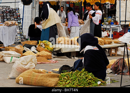 Ecuador, Otavalo, Seitenansicht einer Frau eingewickelt in schwarzem Stoff, sitzen auf dem Markt neben einer Gemüse-Garküche, Menschen Stockfoto