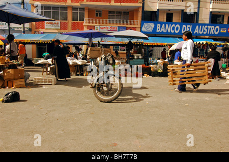 Ecuador, Otavalo, indigene Frau zu Fuß auf einer Straße mit einem alten rostigen Motorrad geparkt auf dem Markt Stockfoto