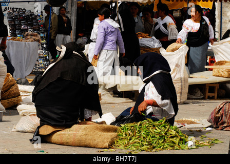 Ecuador, Otavalo, Seitenansicht einer Frau sitzt im Markt mit Menschen im Hintergrund Stockfoto