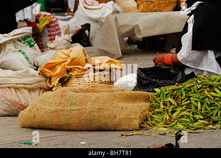 Ecuador, Otavalo, Nahaufnahme einer Frau sitzt auf dem Boden im Markt neben einem Haufen von frischen grünen Bohnen schälen Sie Stockfoto