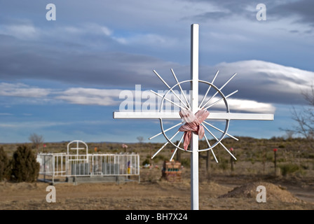 Ein glänzendes Kreuz fängt der späten Nachmittag Sonnenlicht auf einem kleinen Friedhof außerhalb Willard, New Mexico. Stockfoto