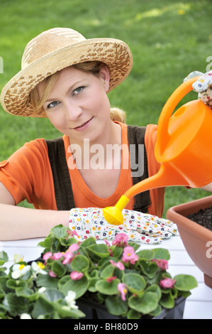 Junge Frau Bewässerung Blumen Stockfoto