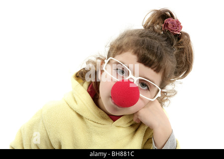 traurige Clown Nase kleine Mädchen mit großen Gläsern posiert Porträt auf weiß Stockfoto