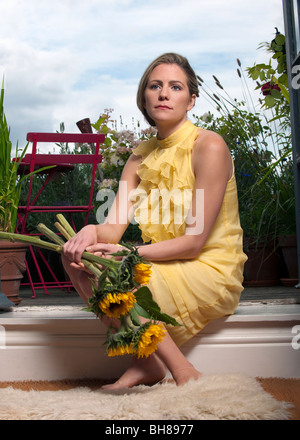 Frau mit Sonnenblumen auf Balkon Stockfoto