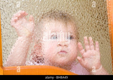 Ein Kind gegen eine abgeschrägte Glasfenster gedrückt Stockfoto