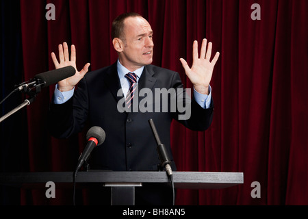 Ein Mann in einem Anzug an einem Lesepult gestikulieren Stockfoto