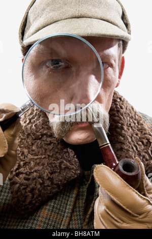 Ein Mann verkleidet als Sherlock Holmes mit einer Lupe verzerrt sein Auge Stockfoto