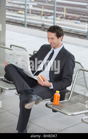 Geschäftsmann auf Bank mit Zeitung Stockfoto