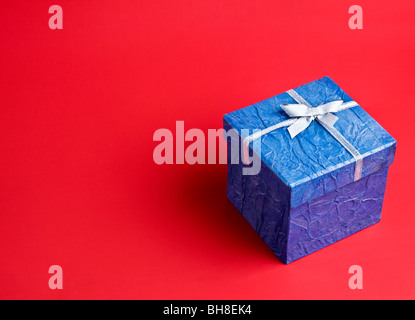 Blaues Geschenk auf rotem Grund Stockfoto