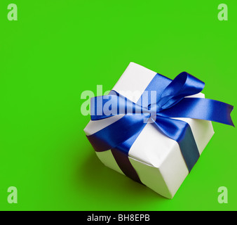 weiße Geschenk in ein blaues Band auf grünem Hintergrund Stockfoto