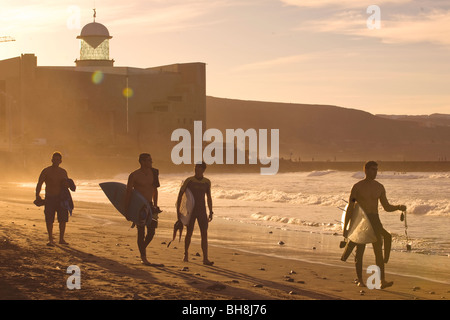 Surfer nach Hause bei Sonnenuntergang am Strand von Las Canteras, Auditorio Alfredo Kraus im Hintergrund Stockfoto