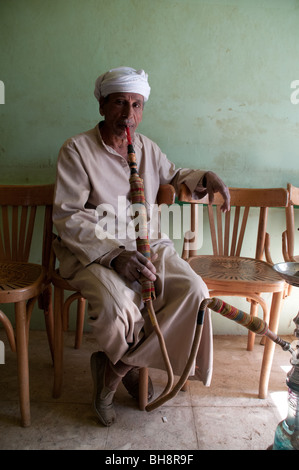 Eine ältere ägyptischen Mann Rauchen einer Wasserpfeife Rohr in einem Café in der Stadt al-Qasr, Dakhla Oase, Western Desert Region der Sahara, Ägypten. Stockfoto