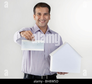 Mann, der ein Hausmodell und Scheck Stockfoto