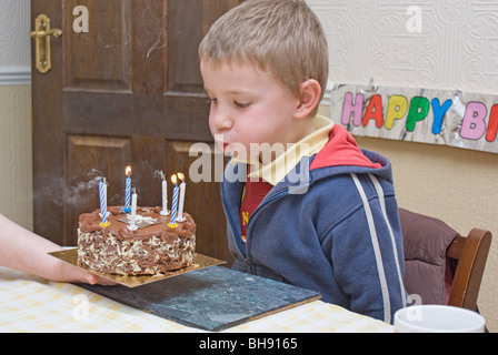 Boy bläst die Kerzen seiner Geburtstagstorte Stockfoto
