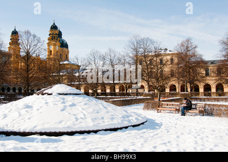 Hofgarten in München bedeckt in Schnee, wie ein einsamer Mensch sitzt und ein Buch liest. Deutschland. Stockfoto